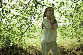 Girl standing under branches, looking up