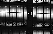 Silhouette of person behind metal grill, b&w