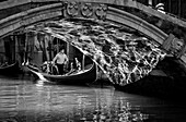 Gondola with Gondolier under the bridge, reflections of light, Venice, Italy