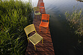 Colourful chairs on a wooden jetty, Simssee, Bavaria, Germany