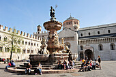 Personengruppen sitzen am Brunnen auf Stadtplatz, Dom im Hintergrund, Trient, Trento, Trentino, Italien, Europa