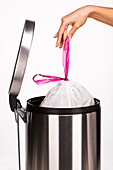 Woman's hand pulling a bag from the garbage