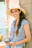 Young smiling woman holding shears, straw hat