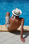 Teen boy reading near a pool