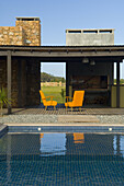 Swimming pool of a contemporary house with orange armchairs