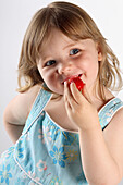 Little girl eating a stawberry, studio
