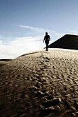 Woman Walking on Desert Sand Dune, Rear View, California, USA
