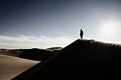 Woman Standing at Top of Desert Sand Dune, California, USA