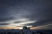 Zwei Skifahrer stehen auf einem Berggipfel in der Abenddämmerung, Chandolin, Anniviers, Wallis, Schweiz
