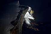 Snowboarder springt von einem Felsvorsprung bei Nacht, Chandolin, Anniviers, Wallis, Schweiz