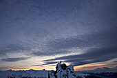 Snowboarder steht auf einem Berggipfel in der Abenddämmerung, Chandolin, Anniviers, Wallis, Schweiz
