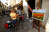 Two cyclists looking at an oil painting, Uzes, Provence, France