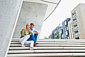 Couple sitting on staircase, HafenCity, Hamburg, Germany