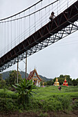 Woman cycles across bridge over River Kwai Noi near Sai Yok National Park, near Kanchanaburi, Thailand