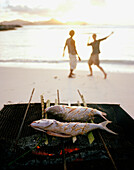 Creole fish barbecue on the beach at sunset, in the background neighbour island Praslin, La Digue, La Digue and Inner Islands, Republic of Seychel les, Indian Ocean