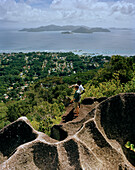 Hikers on granitic rock on the way to Nid d'Aigles lookout point in 300m above sealevel, view over the village La Passe and Praslin Island, central La Digue, La Digue and Inner Islands, Republic of Seychelles, Indian Ocean