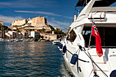 Boat with Union Jack in harbor, citadel, Bonifacio, Corsica, France