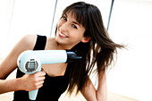Portrait of a young woman using a hair drier