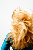 Young woman with blond hair, view from the back, blurred motion, close up (studio)