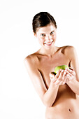 Naked woman holding a green apple, (studio)