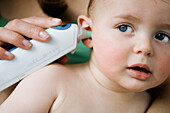 Mother taking her baby's temperature with an ear-thermometer
