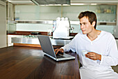 Young man using laptop in kitchen