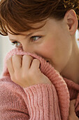 Portrait of young woman covering her mouth with jumper