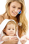 Nahaufnahme einer jungen Frau und ihres Sohnes, die mit Seifenblasen spielen