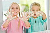 Two girls showing her hands covered with cake icing