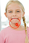 Portrait of a girl holding a candy in her mouth
