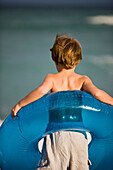 Boy holding an inflatable ring on the beach