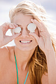 Woman holding shells in front of her eyes