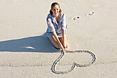 Woman drawing a heart shape on the beach