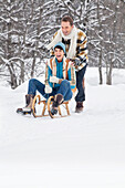 Young man pushing woman on sled