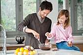 Man stirring a mixture in a bowl with his daughter