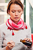 Young woman taking cough medicine