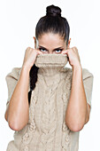 Young woman covering her face with sweater