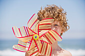 Portrait of a boy holding a pinwheel in front of his face