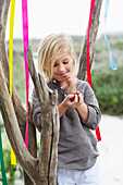 Girl leaning against a tree and eating fruit