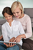 Woman assisting her daughter in using a digital tablet