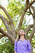 Low angle view of a young woman standing under a tree