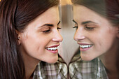Smiling woman looking at her own reflection in the mirror