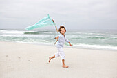 Boy running while holding flag on beach