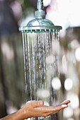 Close-up of a woman's hand under running shower