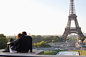 Couple sitting together with the Eiffel Tower in the background, Jardins du Trocadero, Paris, Ile-de-France, France
