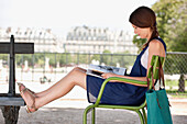 Woman sitting in a chair and reading a magazine, Jardin des Tuileries, Paris, Ile-de-France, France