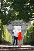 Couple holding a map in front of their faces, Terrasse De l'Orangerie, Jardin des Tuileries, Paris, Ile-de-France, France