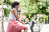 Woman riding a bicycle and talking on a mobile phone, Paris, Ile-de-France, France