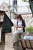 Woman reading a book at a book stall, Notre Dame de Paris, Paris, Ile-de-France, France