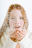 Portrait of a young woman blowing snow from her cupped hands